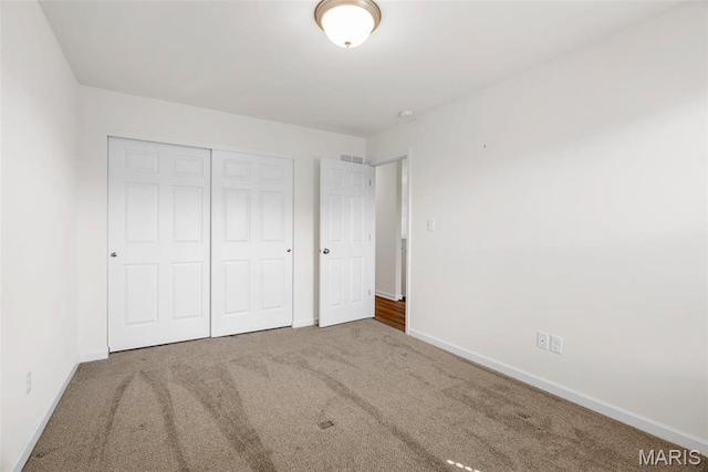 unfurnished bedroom with carpet floors, baseboards, and a closet