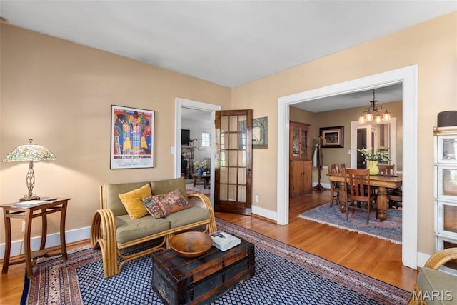 living room with wood finished floors, a chandelier, and baseboards
