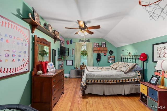 bedroom featuring radiator, wood finished floors, lofted ceiling, and ceiling fan