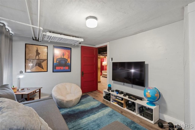 living area featuring wood finished floors, a textured ceiling, and baseboards