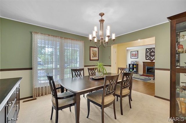 14710 Arbre Ln, Florissant, MO 63034 - dining space with plenty of natural light, a chandelier, ornamental molding, a fireplace, and light wood-style flooring
