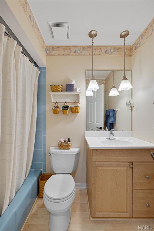 14710 Arbre Ln, Florissant, MO 63034 - bathroom featuring vanity, toilet, shower / tub combo with curtain, and wood finished floors