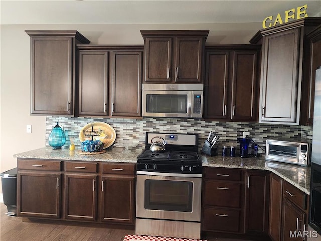 kitchen featuring appliances with stainless steel finishes, dark brown cabinets, decorative backsplash, and light stone countertops