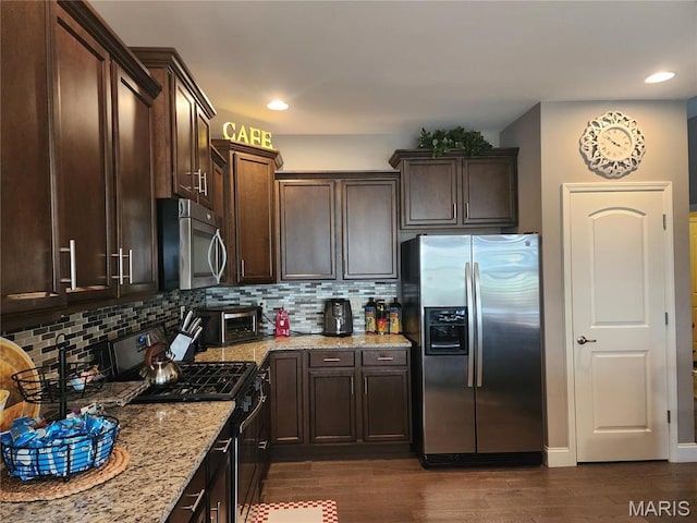 kitchen featuring stainless steel appliances, light stone counters, dark brown cabinetry, decorative backsplash, and dark wood-type flooring