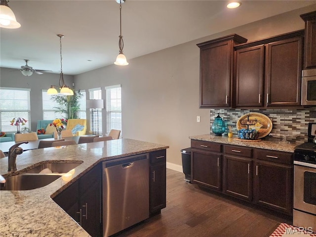kitchen with appliances with stainless steel finishes, ceiling fan, dark wood-type flooring, a sink, and tasteful backsplash