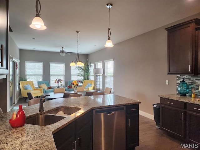 kitchen featuring stainless steel dishwasher, a sink, a ceiling fan, light stone countertops, and baseboards