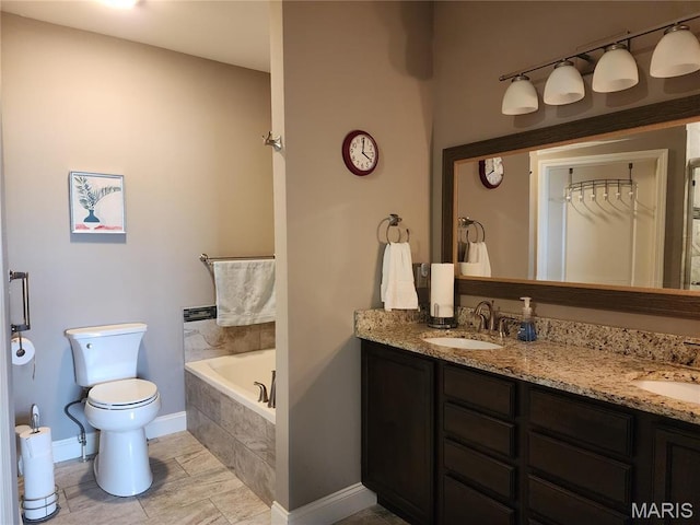 full bath featuring toilet, double vanity, a garden tub, and baseboards