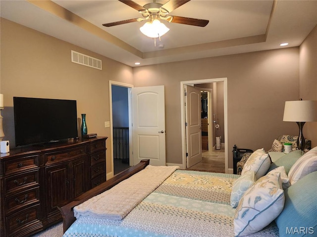 bedroom featuring a tray ceiling, baseboards, recessed lighting, and ceiling fan