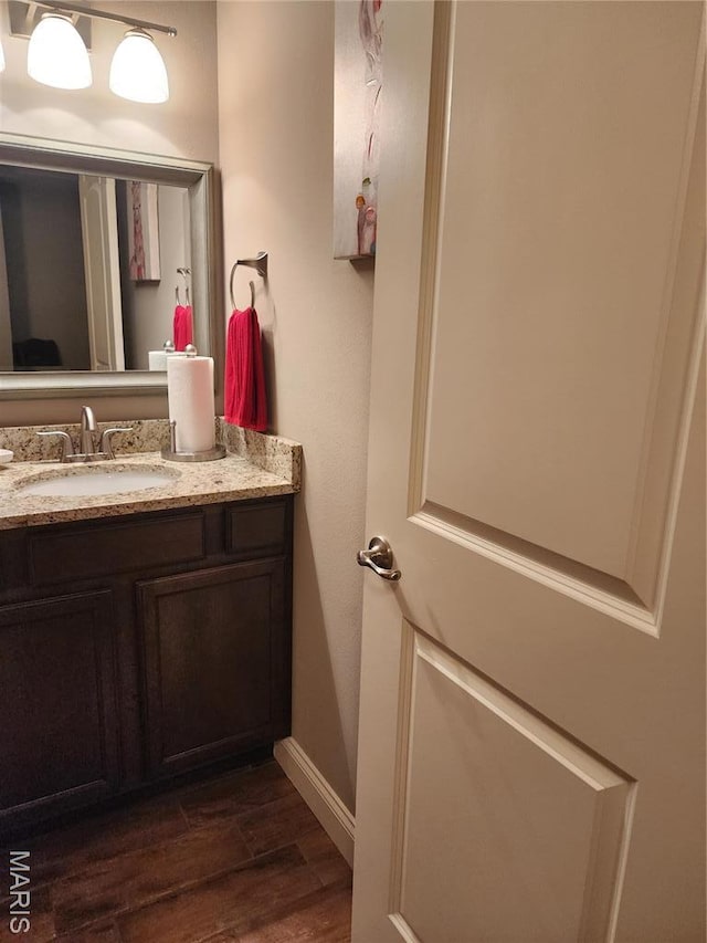 bathroom with wood finished floors, vanity, and baseboards
