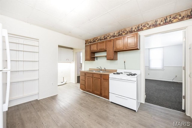 917 N Church St, Belleville, IL 62220 - kitchen featuring white gas range oven, a sink, brown cabinetry, light wood-type flooring, and a paneled ceiling
