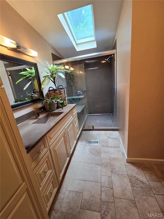 119 Bethel Rd, Hawk Point, MO 63349 - bathroom featuring a skylight, vanity, a shower stall, vaulted ceiling, and stone finish flooring