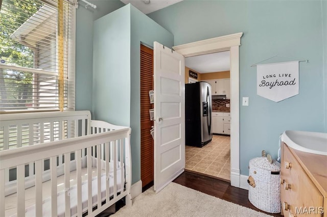 528 Hillsboro Ave, Edwardsville, IL 62025 - bedroom featuring stainless steel fridge, a crib, and wood finished floors