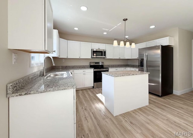 201 Ariel Ct, Desloge, MO 63601 - kitchen featuring stainless steel appliances, light wood-type flooring, white cabinets, a center island, and light stone counters