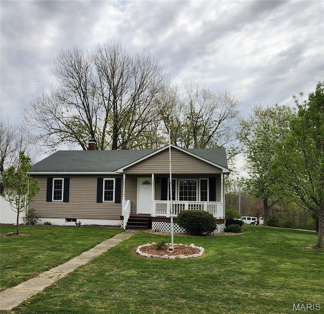 view of front of property with covered porch, a front lawn, a chimney, and a shingled roof