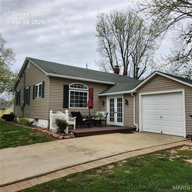 back of house featuring french doors, an attached garage, a chimney, driveway, and a shingled roof