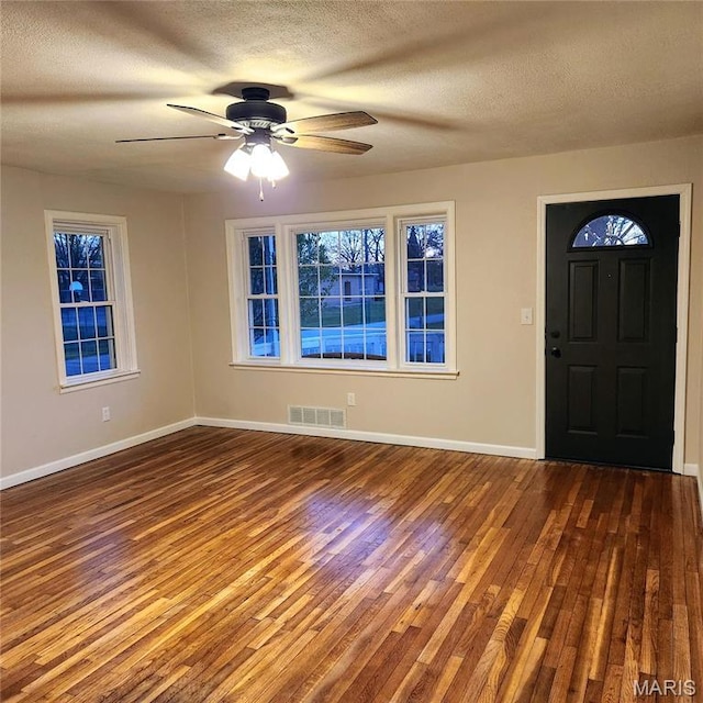 foyer entrance with wood finished floors, baseboards, a textured ceiling, and a ceiling fan