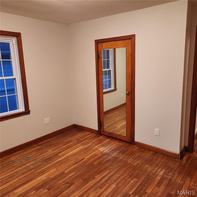 spare room with wood-type flooring and baseboards