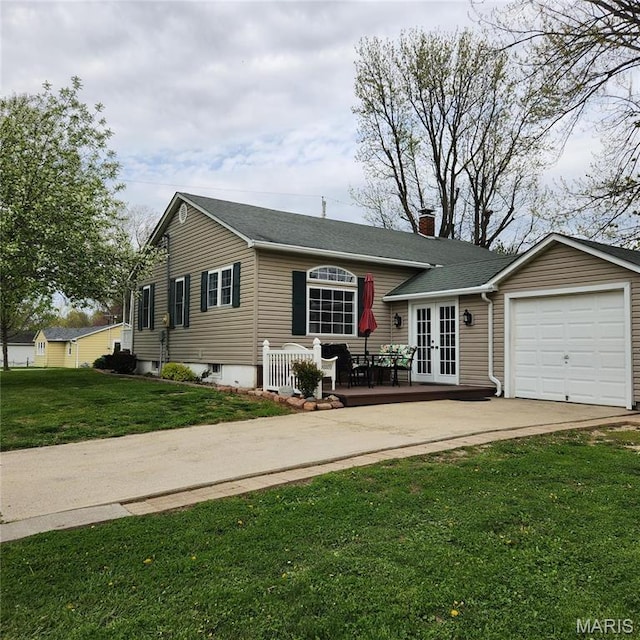 view of front of house with french doors, a chimney, concrete driveway, a garage, and a front lawn