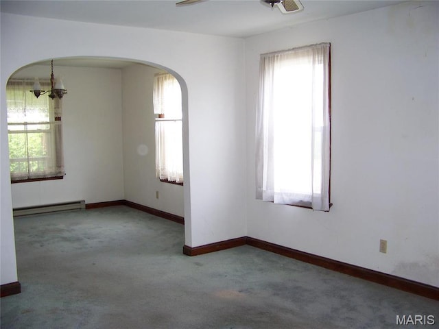 unfurnished room featuring plenty of natural light, baseboard heating, carpet, and arched walkways
