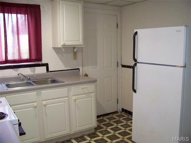 kitchen featuring freestanding refrigerator, a sink, white cabinets, light countertops, and range
