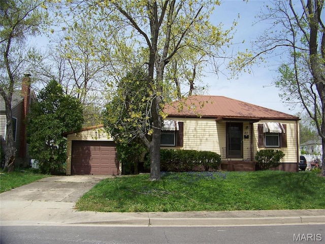 view of front of home featuring a front yard, concrete driveway, a garage, and metal roof