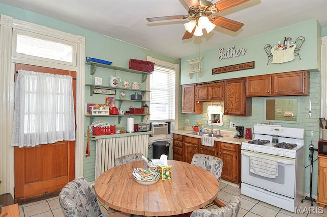 4207 Connecticut St, Saint Louis, MO 63116 - kitchen featuring white gas stove, light tile patterned floors, ceiling fan, decorative backsplash, and a sink