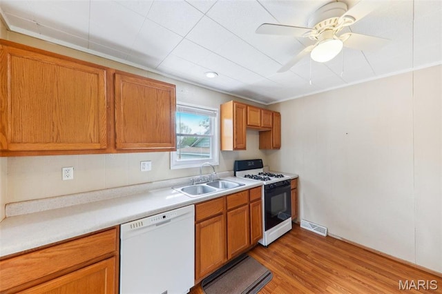 kitchen featuring dishwasher, gas range, a sink, light wood finished floors, and light countertops