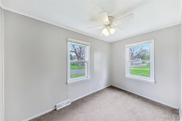 spare room featuring a ceiling fan, carpet flooring, crown molding, and baseboards