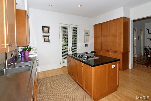 7788 Pershing Ave, Clayton, MO 63105 - kitchen with stainless steel gas cooktop, light wood-style flooring, a kitchen island, brown cabinetry, and a sink