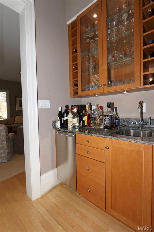 7788 Pershing Ave, Clayton, MO 63105 - indoor wet bar with light wood-style floors, stainless steel dishwasher, and baseboards