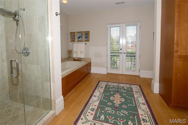 7788 Pershing Ave, Clayton, MO 63105 - full bathroom with french doors, wood finished floors, a stall shower, and a bath