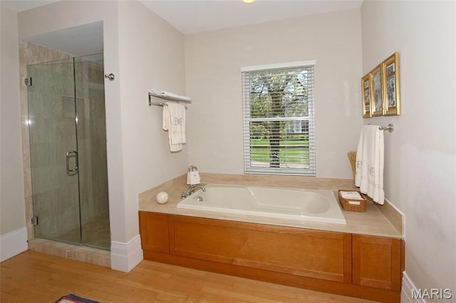 7788 Pershing Ave, Clayton, MO 63105 - bathroom with wood finished floors, a shower stall, a garden tub, and baseboards