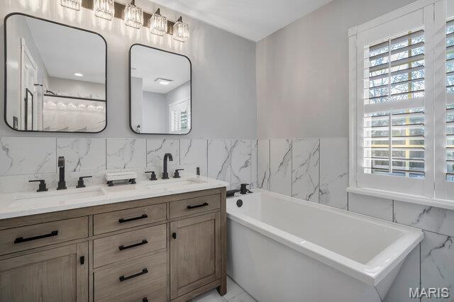 433 Snipes Dr, Saint Charles, MO 63303 - full bathroom featuring tile walls, plenty of natural light, double vanity, a soaking tub, and wainscoting