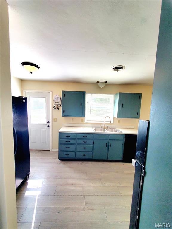 kitchen featuring freestanding refrigerator, a sink, plenty of natural light, and light wood-type flooring