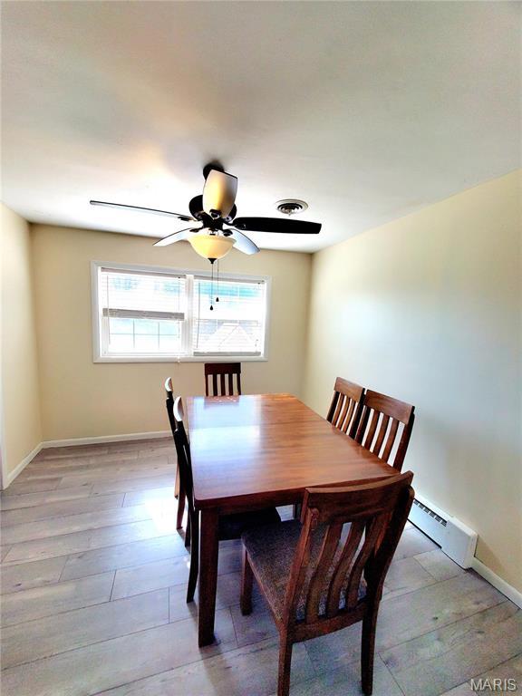 dining room featuring a baseboard radiator, healthy amount of natural light, light wood-style floors, and baseboards