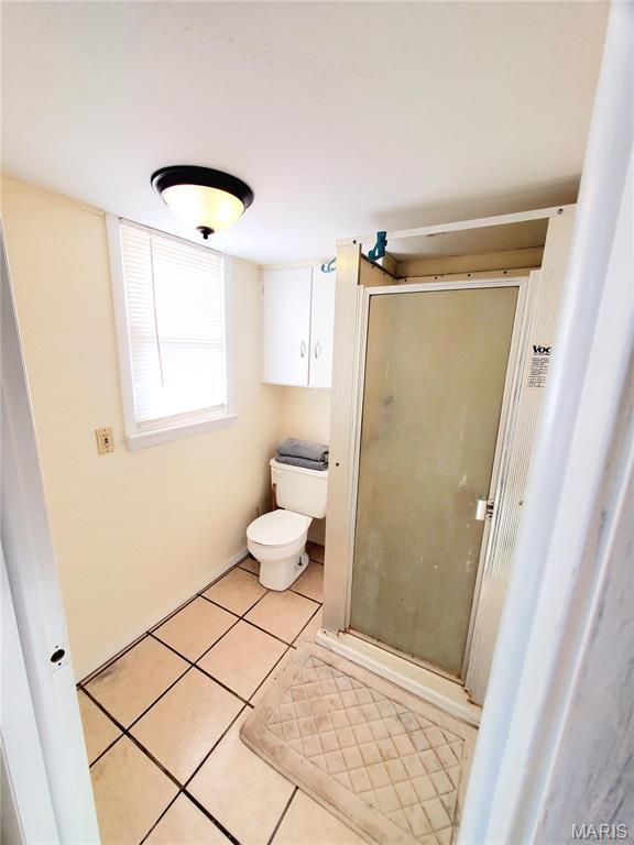 full bathroom featuring a stall shower, toilet, and tile patterned flooring