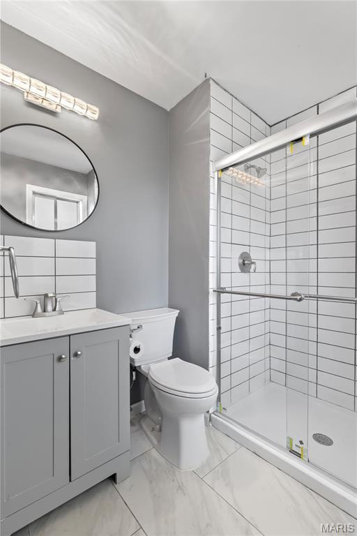 1958 Cathedral Hill Dr, Saint Louis, MO 63138 - bathroom with a stall shower, toilet, marble look tile flooring, and vanity
