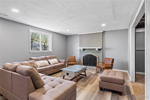 1958 Cathedral Hill Dr, Saint Louis, MO 63138 - living area with a textured ceiling, recessed lighting, a fireplace, light wood finished floors, and baseboards