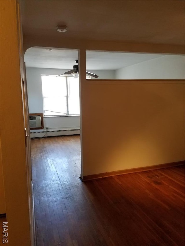 hallway with a baseboard radiator, dark wood-style floors, arched walkways, baseboards, and an AC wall unit