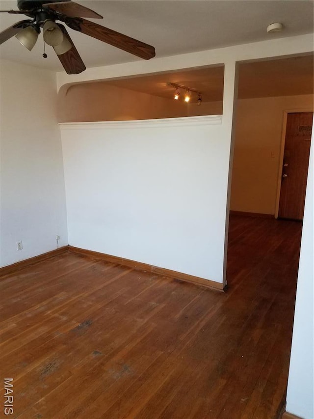 unfurnished room with a smoke detector, a ceiling fan, wood finished floors, and baseboards