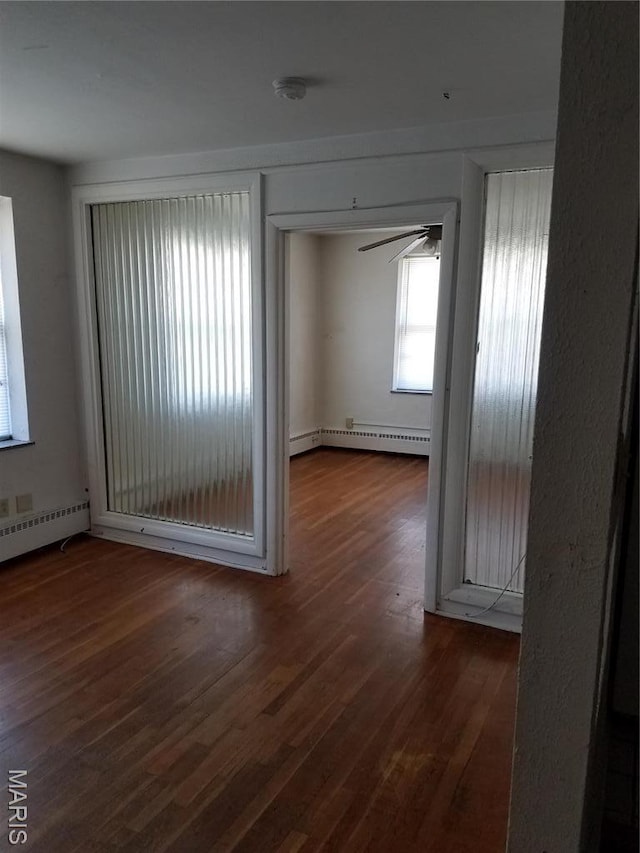 spare room with baseboard heating, wood finished floors, ceiling fan, and a baseboard radiator