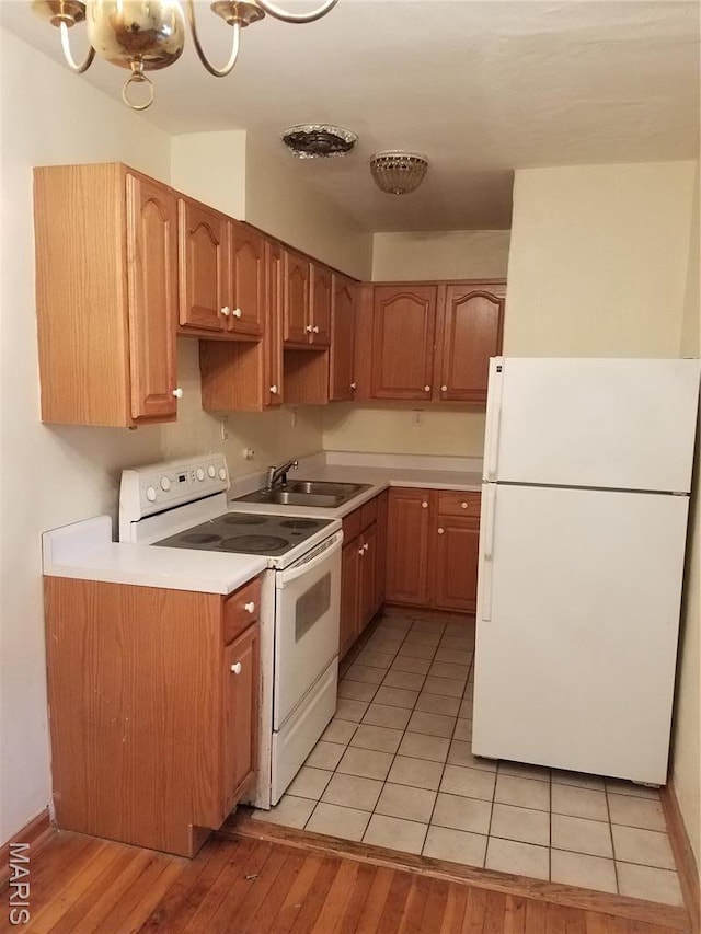kitchen featuring white appliances, a sink, light wood-style floors, and light countertops