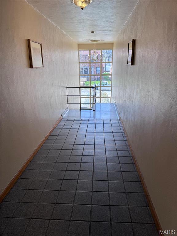 unfurnished room with a chandelier, baseboards, and dark tile patterned floors