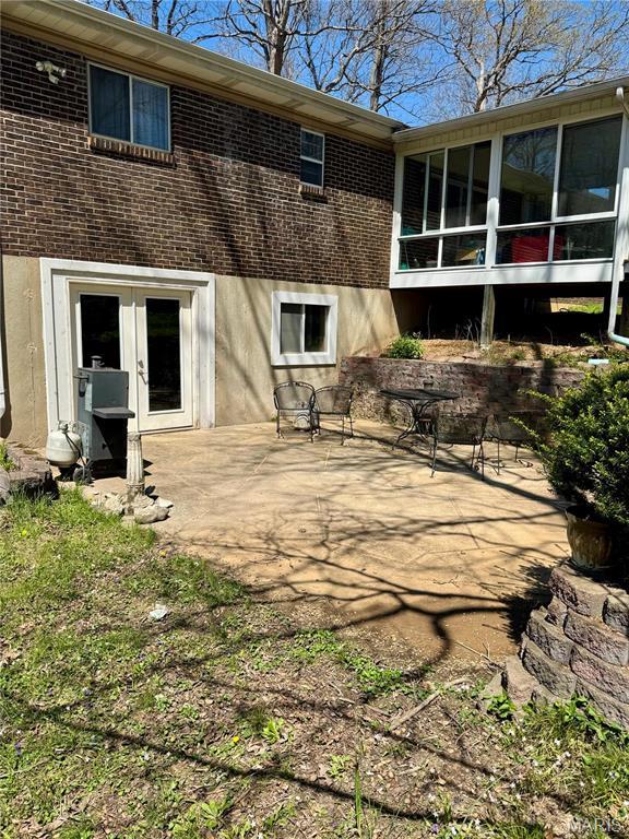 back of house featuring brick siding, a patio area, a sunroom, and french doors