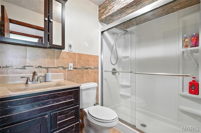 full bathroom with tile walls, a shower stall, toilet, and vanity