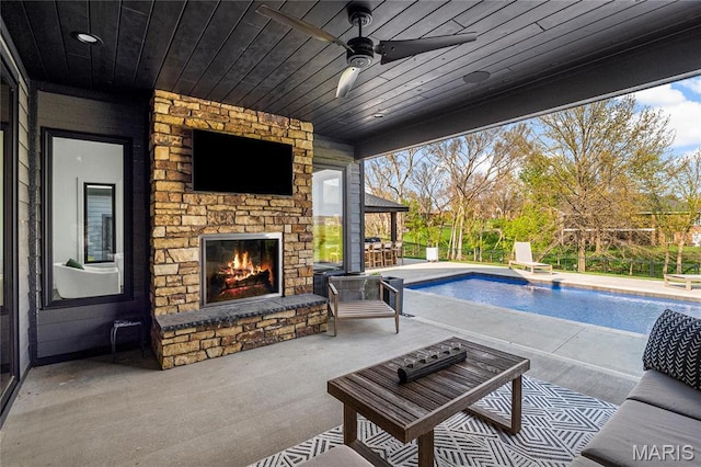 outdoor pool featuring an outdoor stone fireplace, a patio, and a ceiling fan