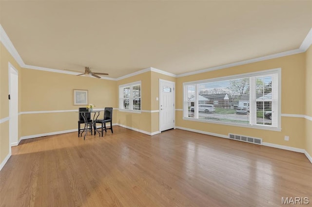 unfurnished living room with ornamental molding, wood finished floors, a ceiling fan, and baseboards