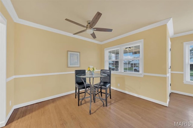 dining area with wood finished floors, crown molding, a ceiling fan, and baseboards