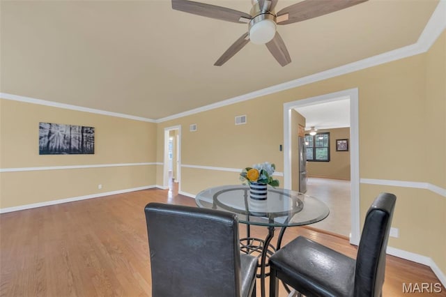 dining area with ceiling fan, light wood-style floors, baseboards, and crown molding