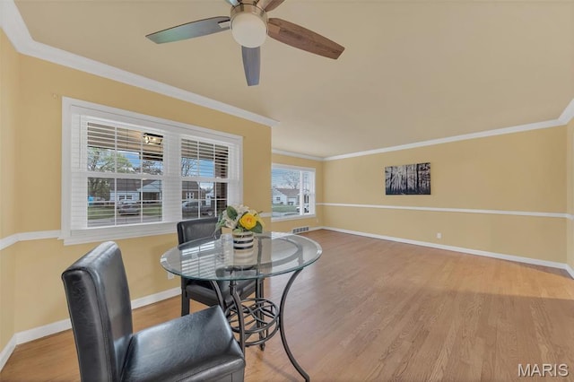 dining room with wood finished floors, crown molding, baseboards, and a ceiling fan